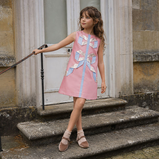 Pink sleeveless shift dress with light-blue ribbon trim and glitter bow details