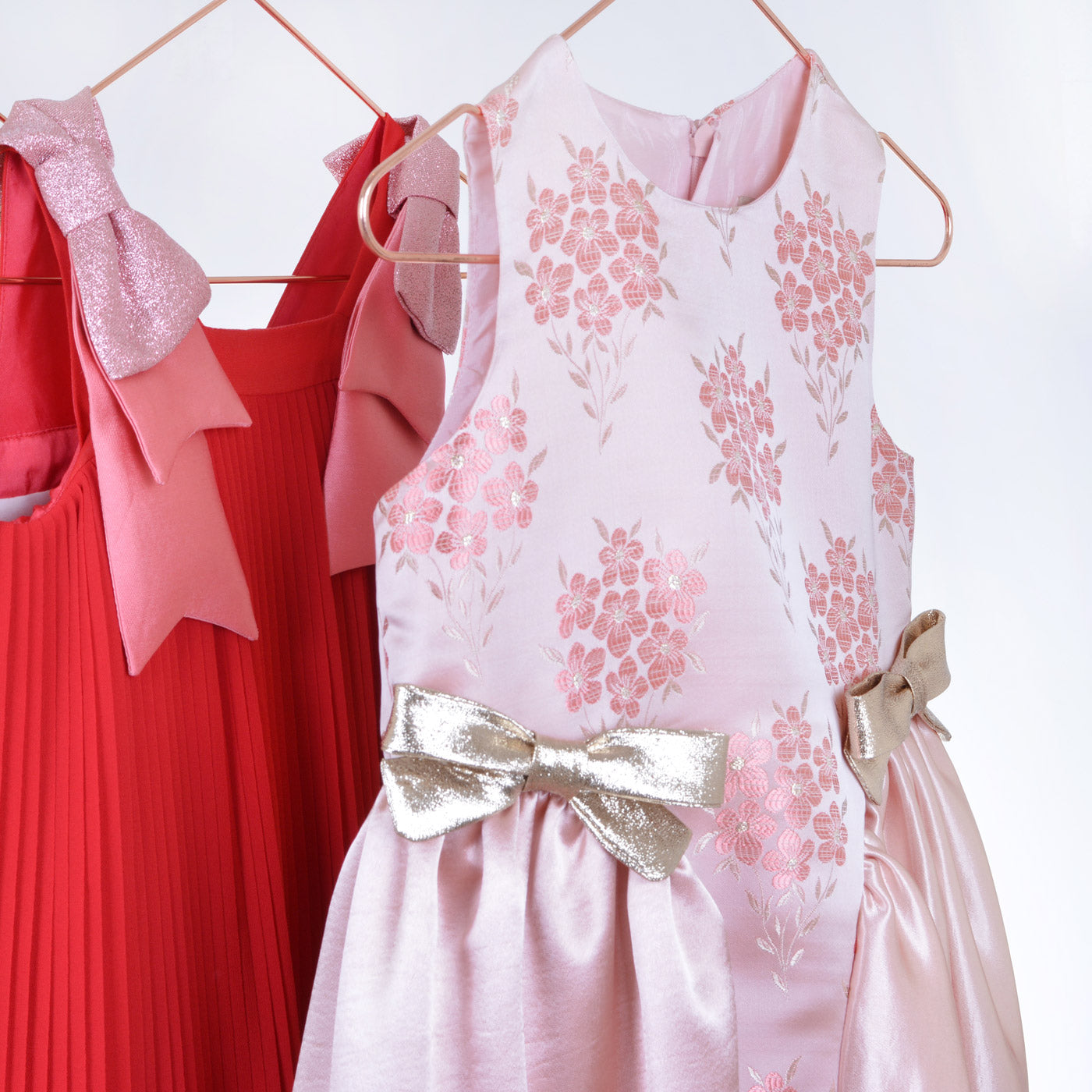 Pink floral sleeveless midi dress on hanger with satin skirt and gold waist bow
