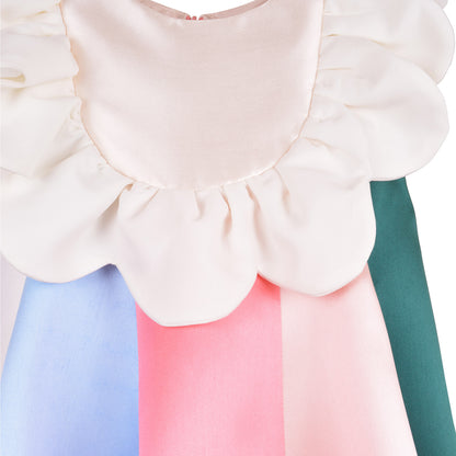 White ruffled bib with layered shoulder ruffles over pastel blue and pink skirt panels