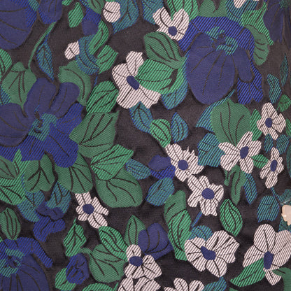 Close-up floral fabric of shift dress with blue flowers, green leaves, and dark purple base