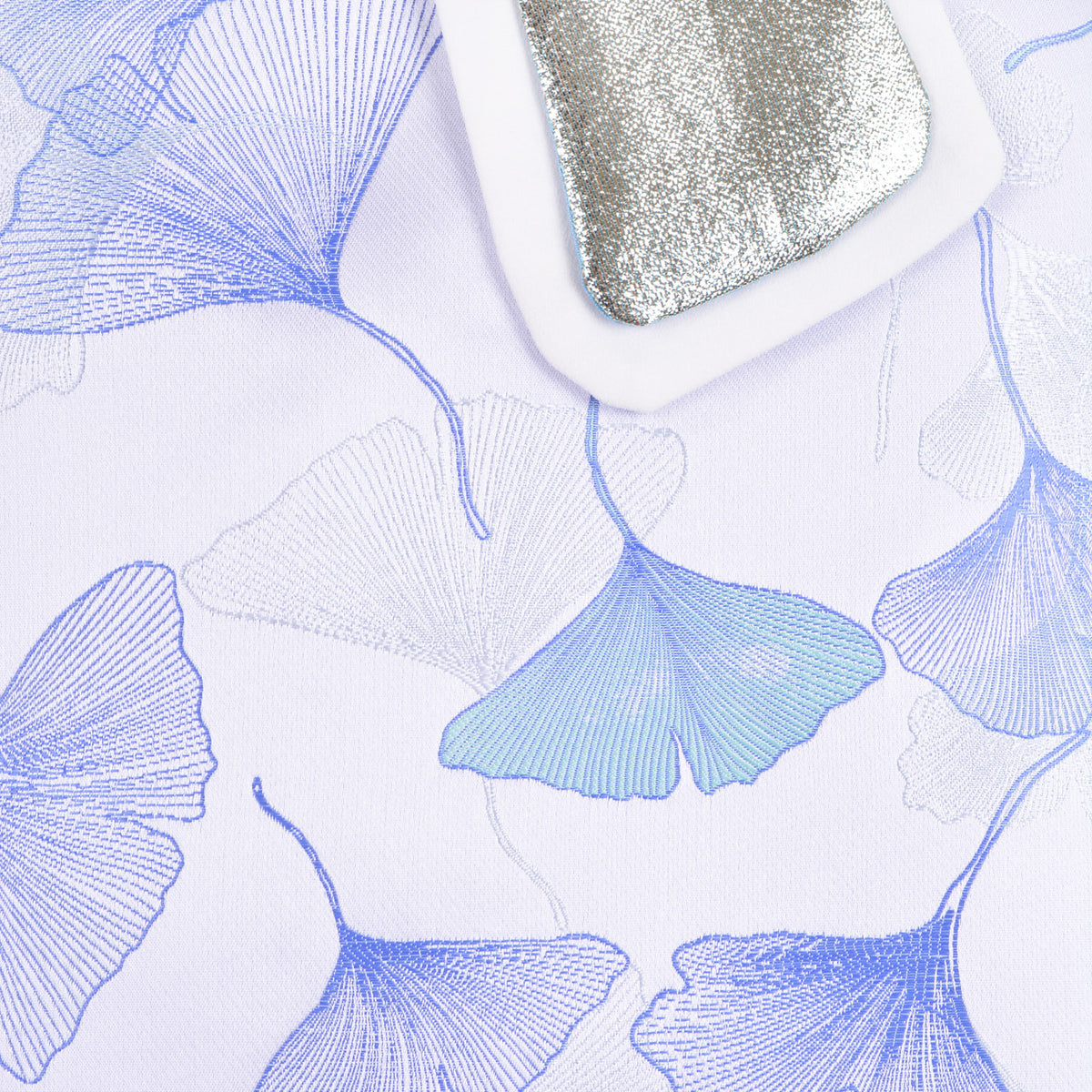 White dress fabric with blue floral print, long sleeve close-up