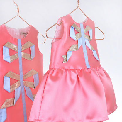 Pink satin dress with large bow at front and gathered skirt with wide ties