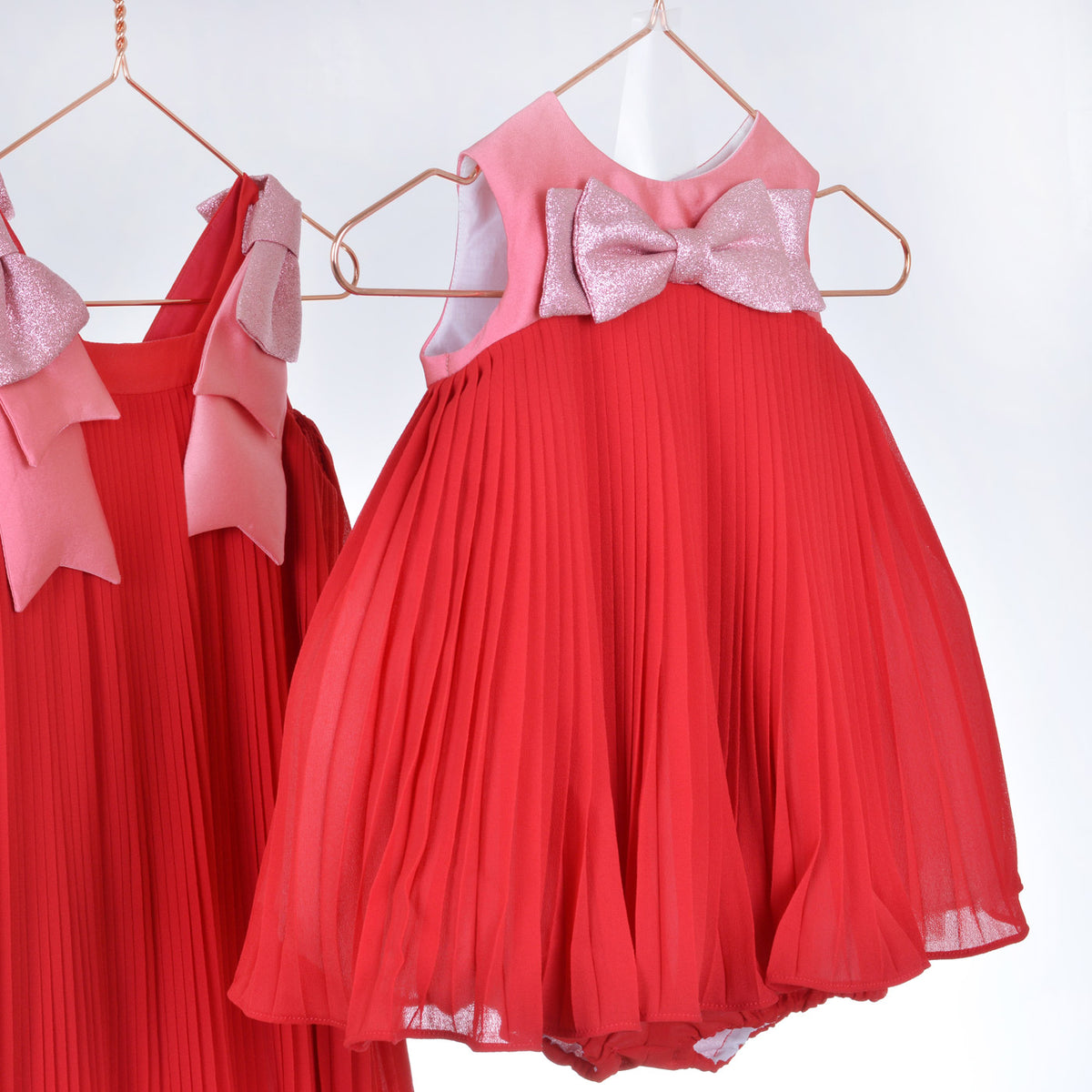 Girls' pleated trapeze dress on hanger with pink glitter bow and flared skirt