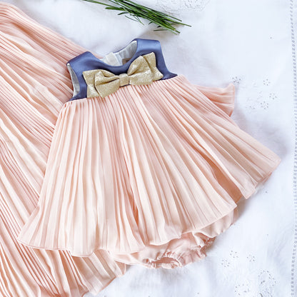 Pink pleated trapeze dress with blue yoke and gold bow; matching ruffled bloomers