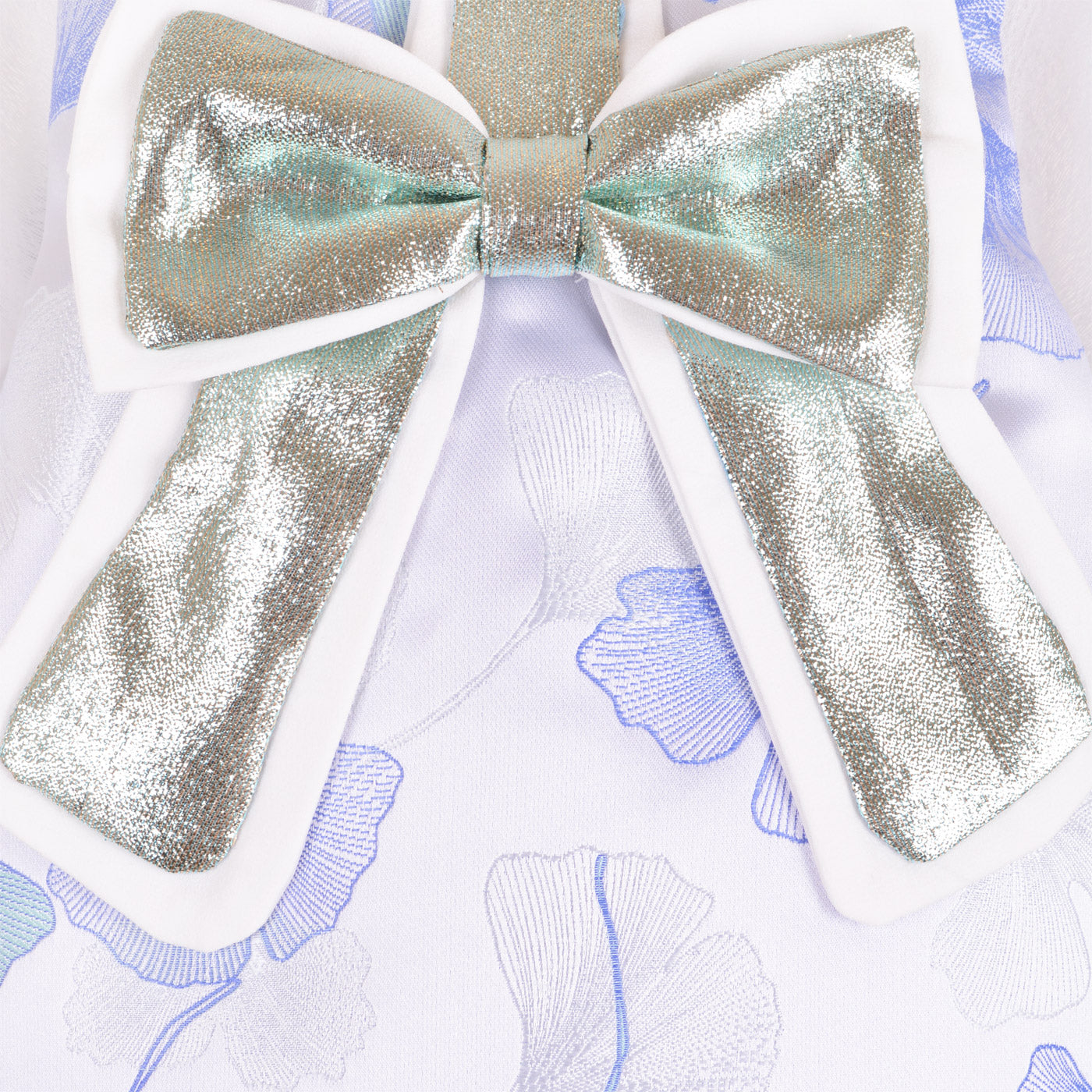 White dress neckline with large iridescent gold glitter bow detail and center knot