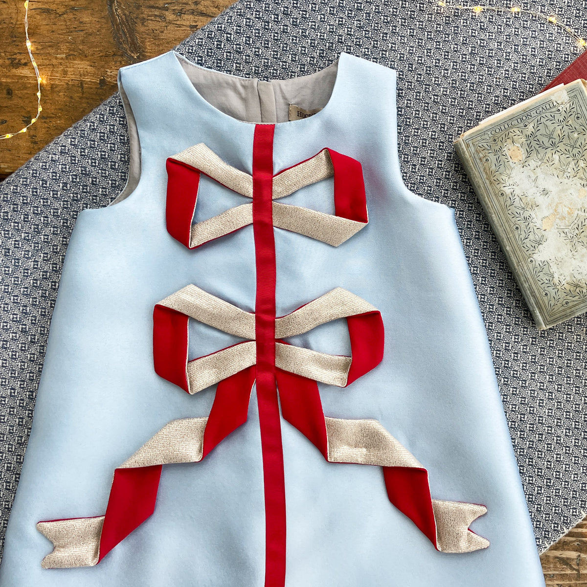 Light blue shift dress with red vertical ribbon and gold origami bow details