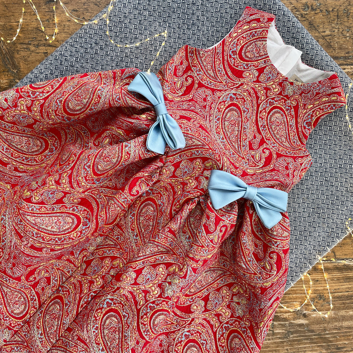 Red paisley gathered-hip midi dress with white collar and light blue bow ties