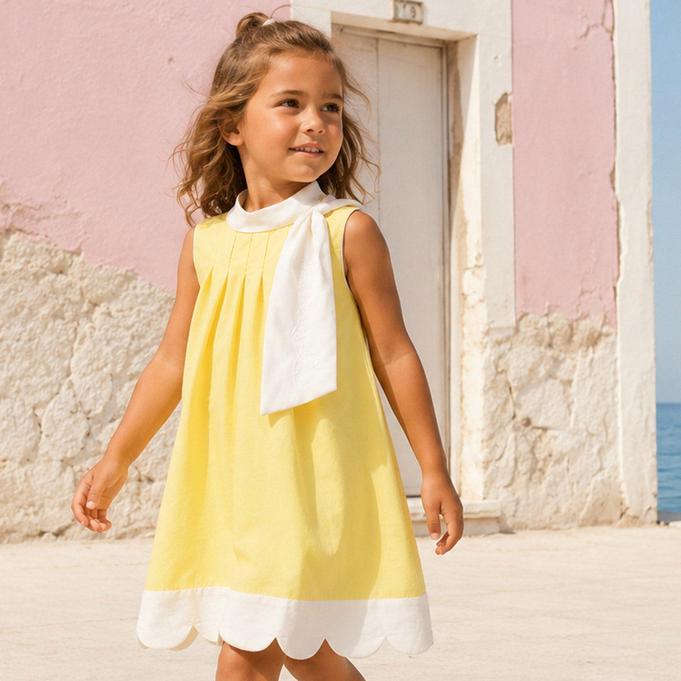 Yellow trapeze dress with white scalloped hem and neck bow