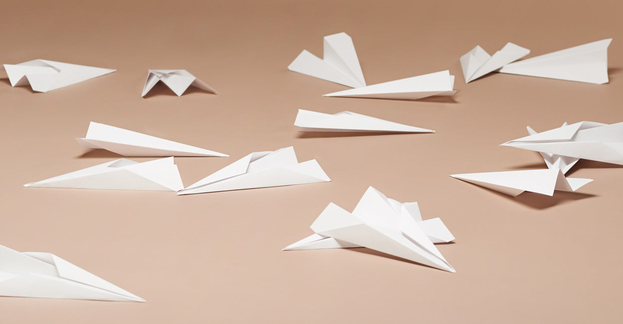 White paper airplanes on a beige background